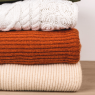 Ein Stapel gefalteter Pullover auf einem Holztisch